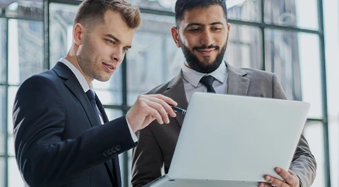 Two men talking over a laptop